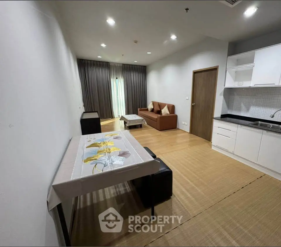 Modern living room with open kitchen, featuring cozy sofa and elegant dining area.