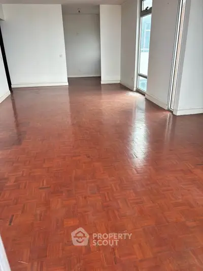 Spacious empty living room with wooden flooring and large windows