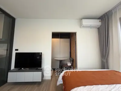 Modern bedroom with air conditioning and TV, featuring a cozy seating area and stylish decor.