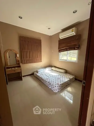 Cozy bedroom with natural light, featuring a comfortable mattress and air conditioning for ultimate relaxation.