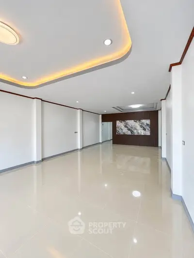 Spacious modern living room with elegant ceiling lights and polished tile flooring.