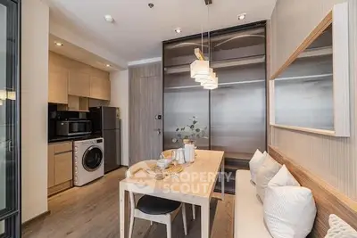 Modern kitchen with integrated appliances and a cozy dining area, featuring sleek cabinetry and a warm, inviting ambiance.