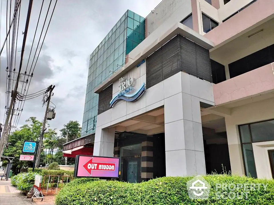 Modern commercial building exterior with glass facade and lush greenery