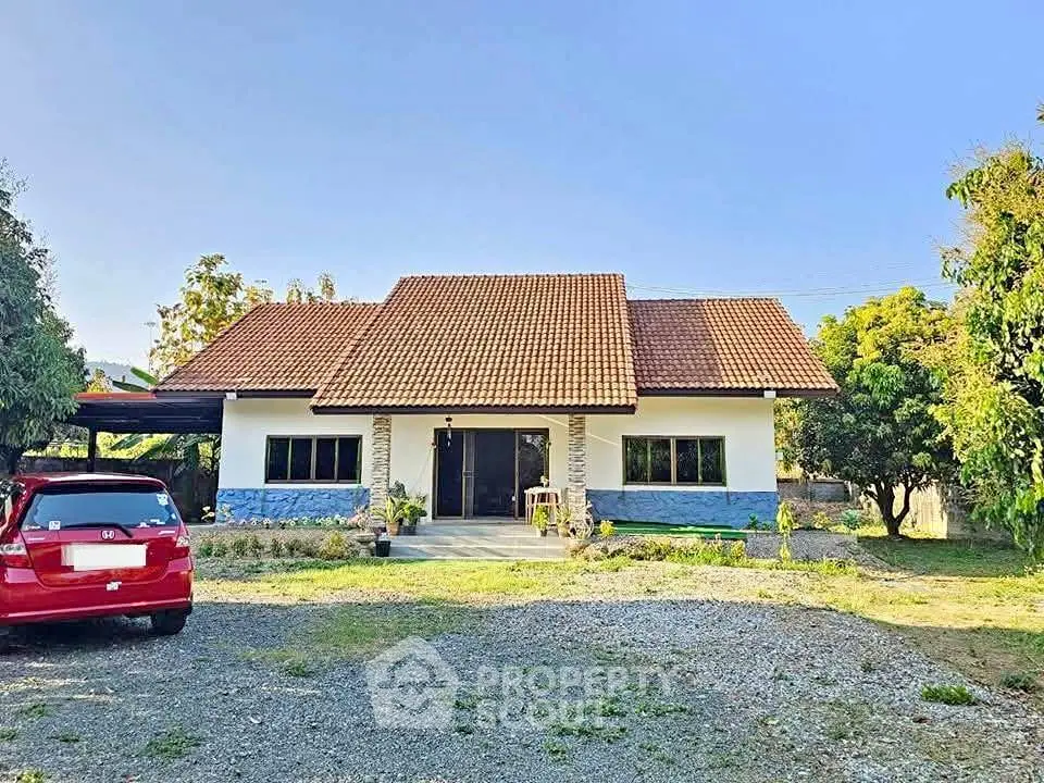 Charming single-story house with red roof and spacious front yard in serene setting.