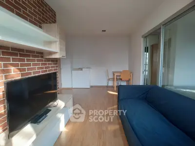 Modern living room with brick accent wall, cozy blue sofa, and natural light.