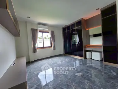 Spacious modern bedroom with sleek built-in wardrobe and elegant marble flooring.