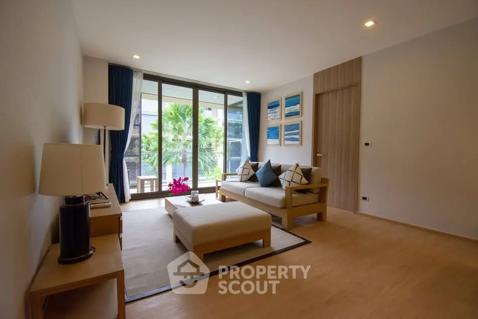 Spacious living room with modern decor and large windows overlooking greenery.