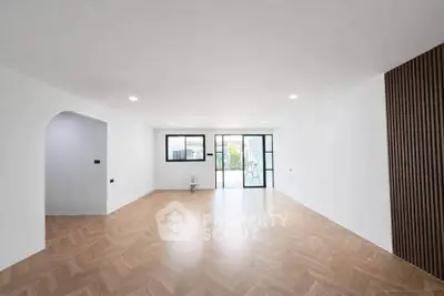 Spacious modern living room with elegant wooden flooring and large windows for natural light.