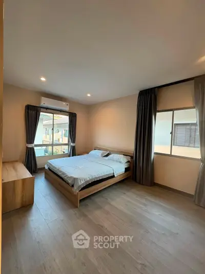 Spacious bedroom with modern decor and large windows for natural light