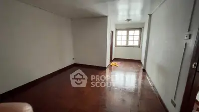 Spacious empty room with wooden flooring and natural light from window.