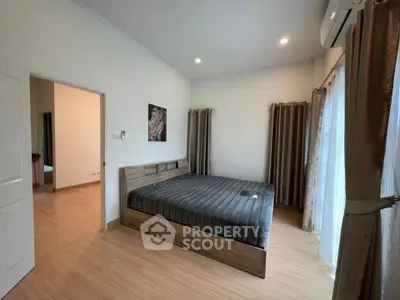 Spacious bedroom with modern decor and large windows for natural light.
