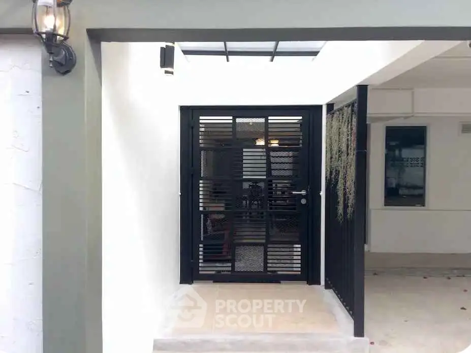 Modern entrance with sleek black gate and covered walkway, perfect for contemporary homes.