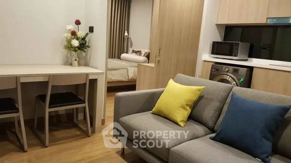 Modern apartment interior with cozy living room and stylish kitchen featuring a washing machine and microwave.