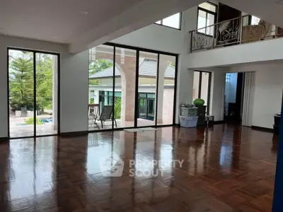Spacious living room with large windows and polished wooden floors