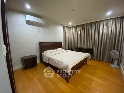 Spacious bedroom with wooden flooring and elegant curtains in modern apartment.