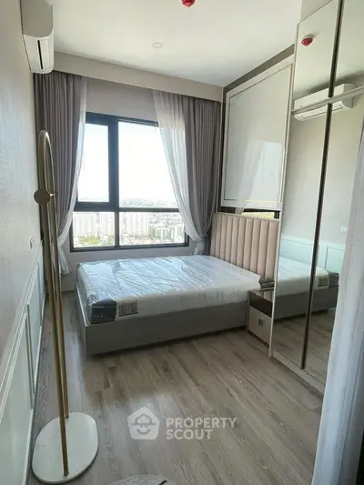 Modern bedroom with large window and stylish decor in a high-rise apartment.