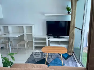 Modern living room with TV, stylish furniture, and natural light from balcony.