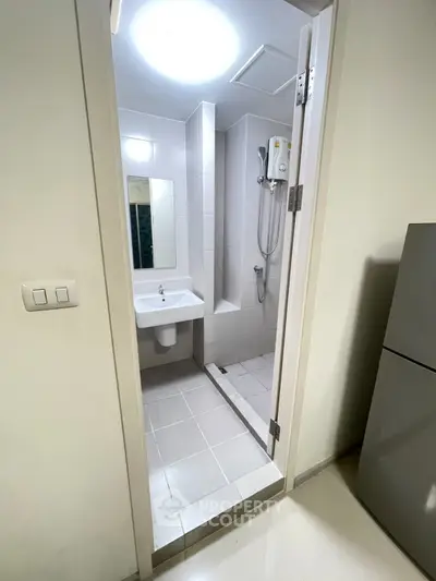 Modern minimalist bathroom with shower and sink in a compact space.