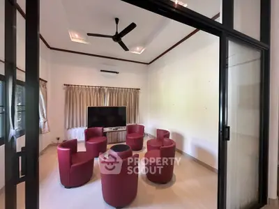 Spacious living room with modern red chairs and large TV, perfect for entertainment and relaxation.