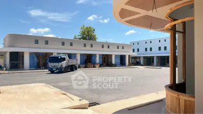 Modern commercial building exterior with spacious parking area under clear blue sky.