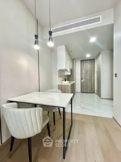 Modern kitchen with sleek design, featuring a marble dining table and elegant lighting in a stylish apartment.