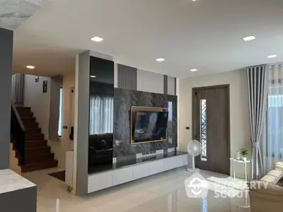 Spacious living room with modern design, glossy floor tiles, and elegant staircase leading to the upper level, complemented by natural light.