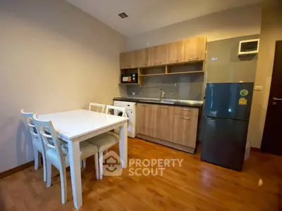 Modern kitchen with dining area, featuring wooden cabinets and sleek appliances.