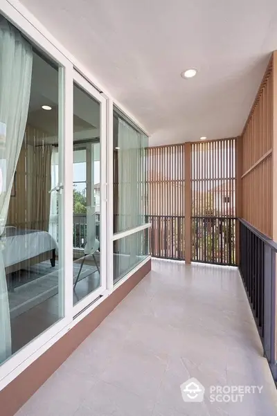 Spacious modern balcony with glass doors and wooden paneling