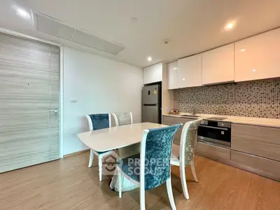 Modern kitchen with dining area, sleek cabinetry, and stylish chairs in a contemporary apartment.