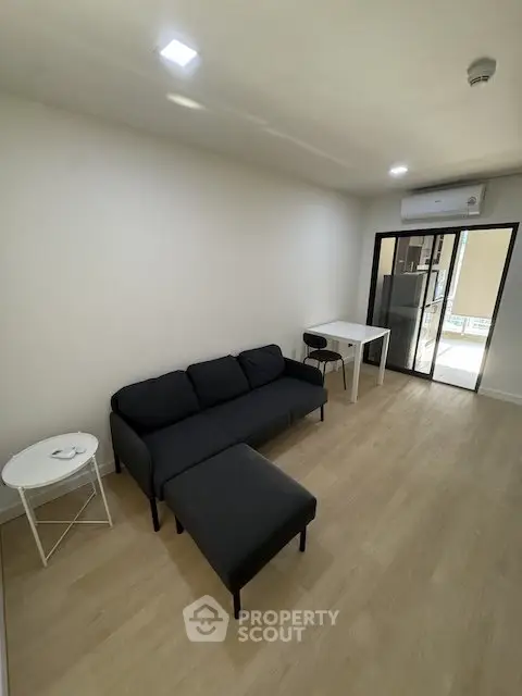 Modern living room with sleek black sofa and minimalist decor in a cozy apartment.