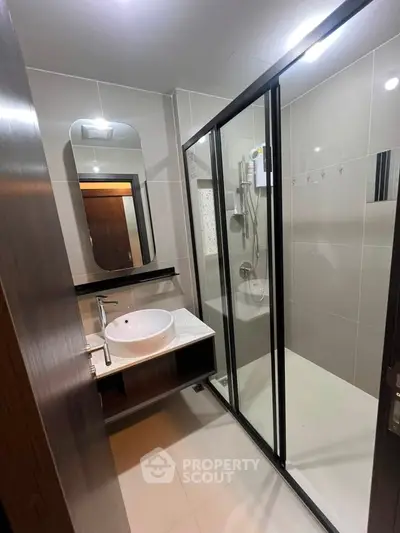 Modern bathroom with sleek shower enclosure and stylish vanity in contemporary apartment.