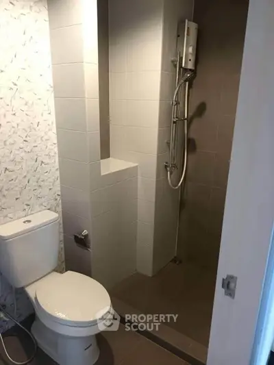 Modern bathroom with shower and toilet in sleek minimalist design.