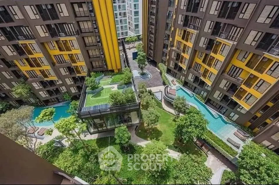 Modern apartment complex with lush garden and pool view from above.