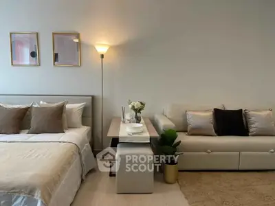 Modern bedroom with cozy bed and stylish sofa in a well-lit interior space.