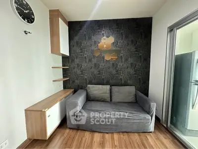 Modern living room with stylish decor and balcony access, featuring a cozy gray sofa and wooden flooring.