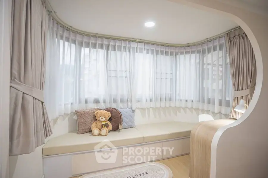 Cozy window nook with plush seating and teddy bear in modern apartment