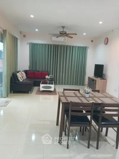 Spacious living room with modern furniture and dining area, featuring elegant curtains and a ceiling fan.