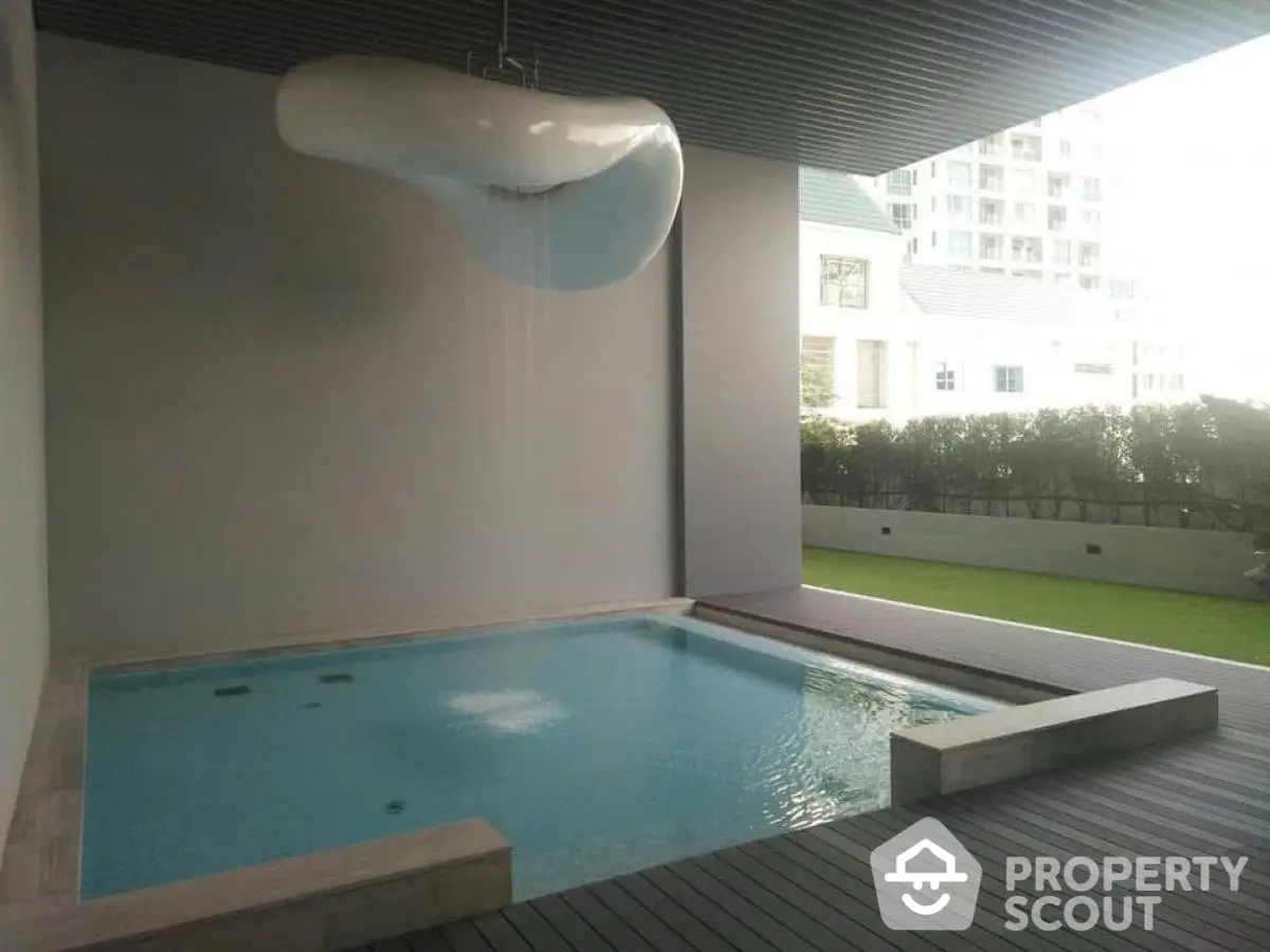 Luxurious modern indoor pool with unique ceiling water feature in upscale residential property.