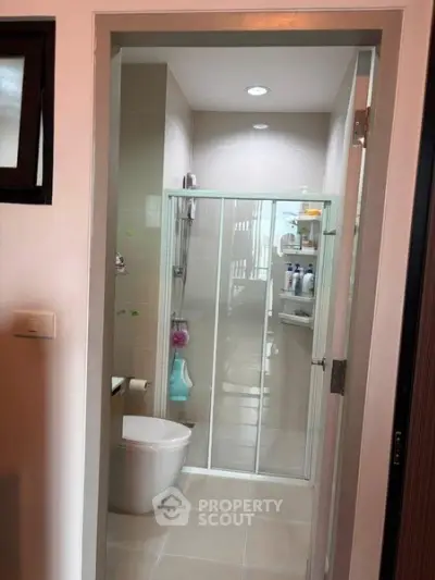 Modern bathroom with glass shower enclosure and sleek fixtures in a contemporary apartment.