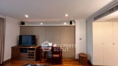 Spacious living room with modern TV setup and elegant wooden furniture.