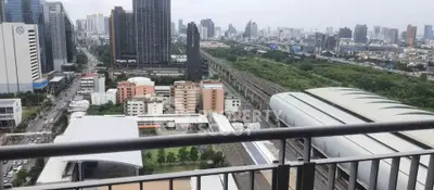 Stunning cityscape view from a high-rise balcony overlooking urban skyline and lush greenery.