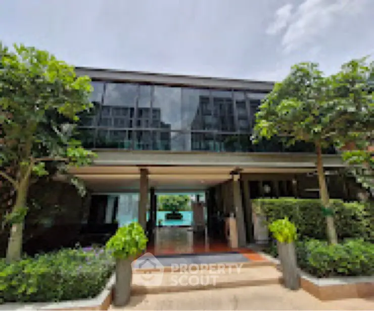 Modern building entrance with lush greenery and glass facade