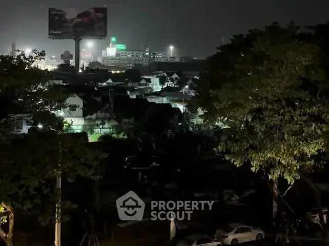 Nighttime cityscape view with illuminated buildings and trees, showcasing urban living ambiance.
