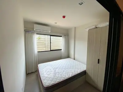 Cozy bedroom with natural light, featuring a comfortable bed and modern air conditioning unit.