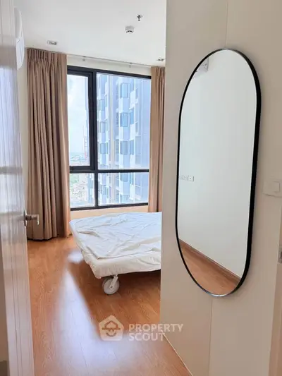 Modern bedroom with large window and wooden flooring in high-rise apartment
