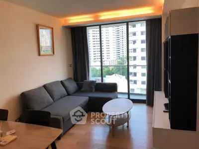 Modern living room with large window and city view, featuring a cozy gray sofa and stylish decor.