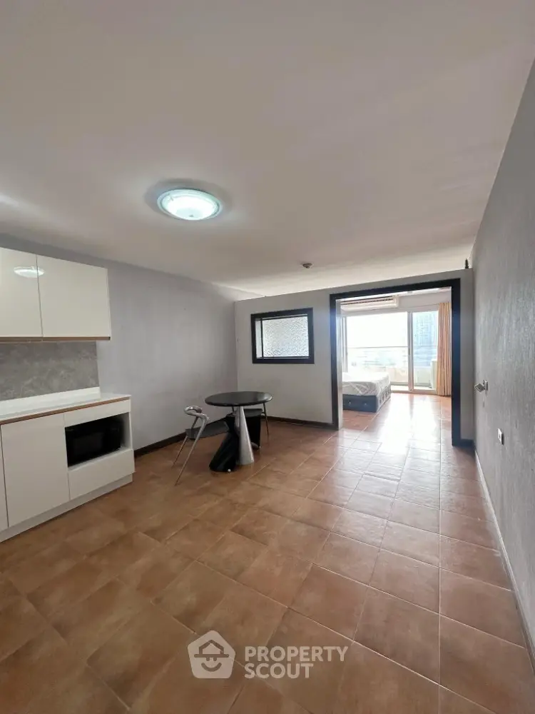 Spacious open-plan apartment with modern kitchen and bright bedroom view.