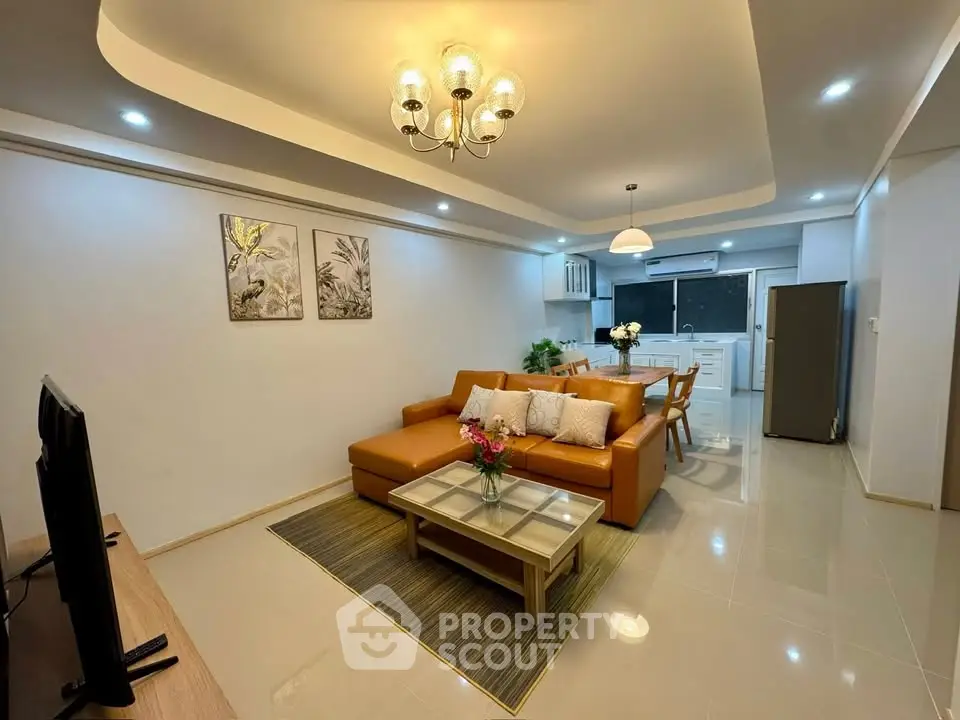 Spacious modern living room with open kitchen, stylish decor, and elegant lighting in a contemporary apartment.