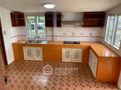 Spacious kitchen with tiled flooring and ample natural light, featuring a gas stove and dual sinks.