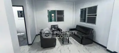 Modern living room with sleek black leather furniture and large windows